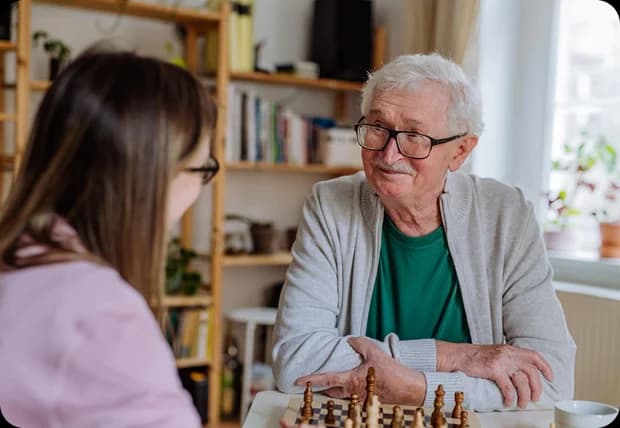 Board and Care Costs in Southern California - Senior woman playing chess with caregiver